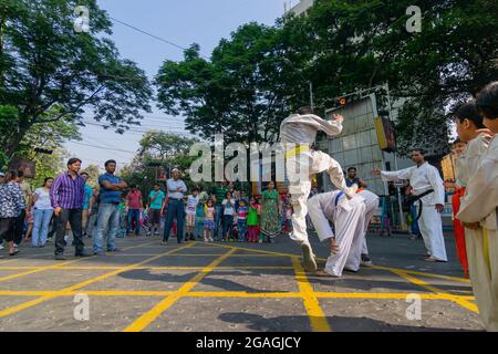 KOLKATA, WEST BENGAL, INDIA - MARCH 21ST 2015 : Young boy in white dress jumping off ground to past two fellow boys over, karate practice at 'Happy St Stock Photo