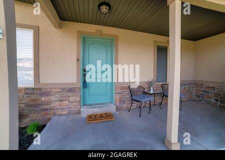 Front porch exterior with mint green door and decorative doormat Stock Photo
