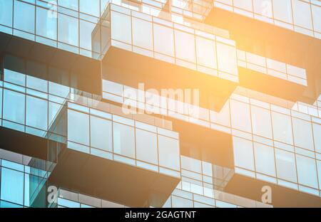 Background image of glass building with orange and yellow light effect, close up to the glass window wall. Concept for corporate building. Stock Photo