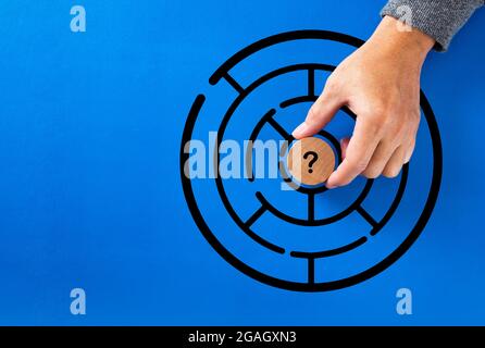 Hand putting question mark in the middle of a maze. Uncertainty, challenge, confusion, mystery or solution concept. Stock Photo