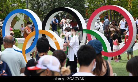 Tokyo, Japan. 31st July, 2021. People take photos in front of the Olympic rings in front of the Olympic stadium. Credit: Swen Pförtner/dpa/Alamy Live News Stock Photo