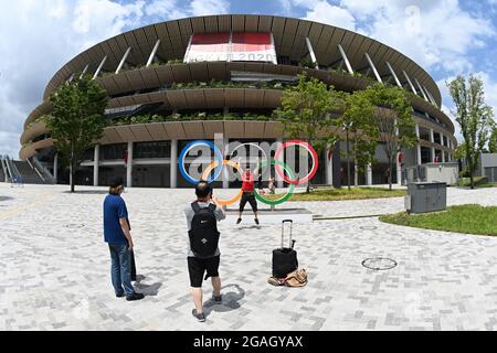 Tokyo, Japan. 31st July, 2021. Men stand in front of the Olympic rings in front of the Olympic stadium. Credit: Swen Pförtner/dpa/Alamy Live News Stock Photo