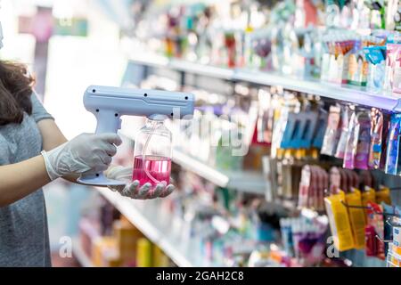 close up hand of staff wearing gloves using electric Alcohol Nano Spray Gun Handhold Blue Light Disinfectant Spray. prevent infection Covid-19 in the Stock Photo