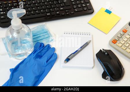 Office space wiping corona virus cleaning and disinfection of your workspace. On the desktop, protective gloves, a mask and disinfectant liquid. Stock Photo