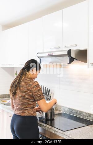 Woman cooking in the kitchen on an induction hob with an odor extractor Stock Photo