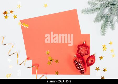 Christmas composition red paper card mockup with green spruce branches and christmas tree decorations, flat lay. Stock Photo