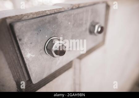 Shallow depth of field (selective focus) image with details of industrial metallic nuts and bolts in a heavy factory. Stock Photo