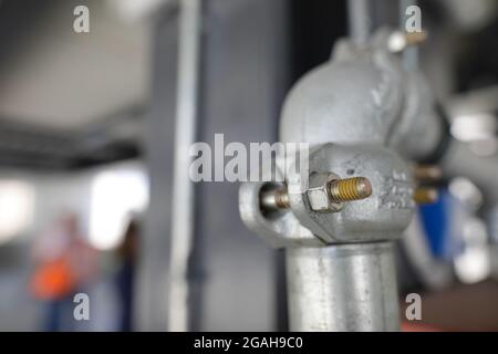 Shallow depth of field (selective focus) image with details of industrial metallic nuts and bolts in a heavy factory. Stock Photo