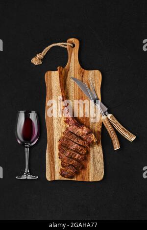 Tomahawk steak cut on slices on wooden board Stock Photo