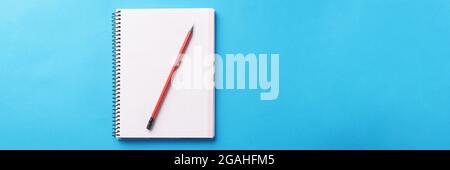 White notebook with wooden pencil lies on blue background Stock Photo