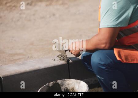 Shallow depth of field (selective focus) image with a worker cementing a sidewalk ledge on a construction site. Stock Photo