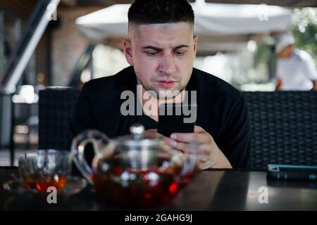 Young man watching smartphone  in cafe . Freelance concept Stock Photo