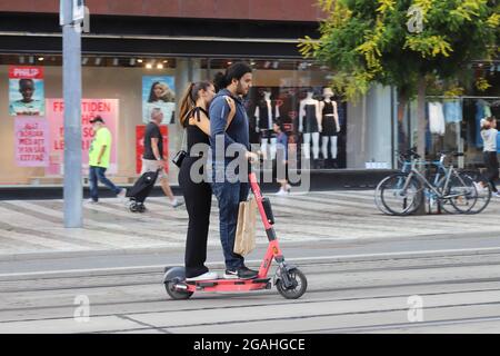 Stockholm, Sweden - July 29, 2021: Two adults on an electric scooter travel in the street environment. Stock Photo