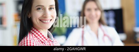 Smiling young woman patient on background of doctor in medical office Stock Photo