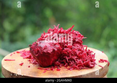 Heap of grated red beetroot in wooden cutting board on nature background Stock Photo