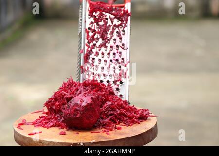 Fresh grated beetroot using stainless steel vegetable grater held in hand Stock Photo