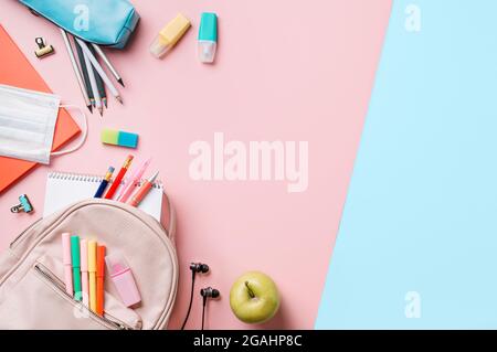 Creative student desk with colorful modern school supplies on blue and pink duotone background. Top view. Flat lay. Copy space. Back to school concept Stock Photo