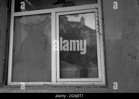 Old broken window in black and white color. One window pane is replaced with cardboard. Stock Photo