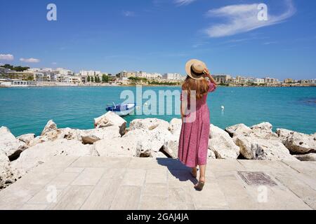 Beautiful woman walking towards Otranto bay admiring panoramic, Apulia, Italy Stock Photo