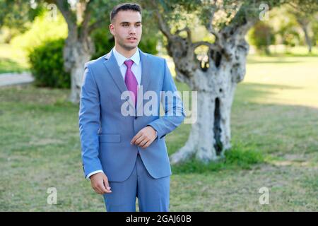 Confident young businessman walking through a garden. The owner of a small business Stock Photo