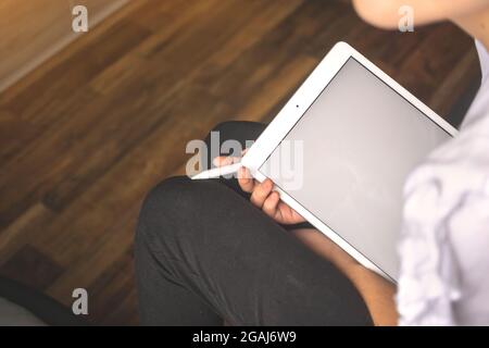 Young female freelancer holding white screen tablet pc with the stylus pen in hand, apartment background Stock Photo