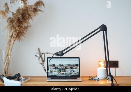 Podcast studio interior. Small home room for podcaster. Voice microphone, laptop and lamp on the wooden table Stock Photo
