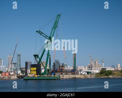 With the Liverpool waterfront behind, the 250 tonne crane Skylift 2 operating on the submersible Skyline Barge 26 at Birkenhead, UK Stock Photo