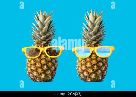 Creative pineapple with sunglasses isolated on blue background, summer vacation beach idea copy space. Stock Photo