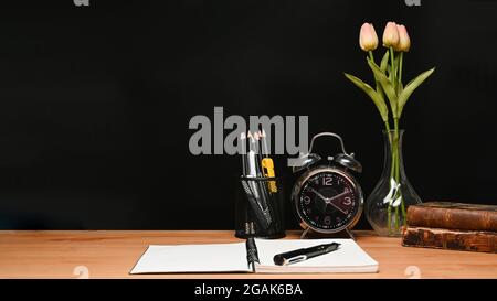 Alarm clock, pencil holder and notebook on wooden table. Stock Photo