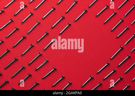 Black steel nails, arranged horizontally, leaving a space in the shape of a rhombus or horizontal square for advertising, dialogue or text Stock Photo