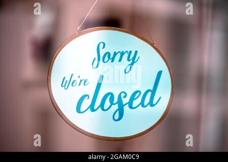'Sorry we're closed' sign behind reflective glass during dusk Stock Photo