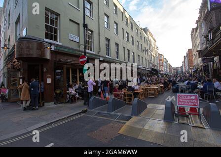 People in a restaurant are seen behind a 'temporary covid restrictions'' sign in London's Soho lifting all restrictions on daily life in England. Stock Photo