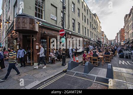 People celebrating 'freedom day' ending over a year of COVID-19 lockdown restrictions in England people drinking on tables placed outside on  Old Comp Stock Photo