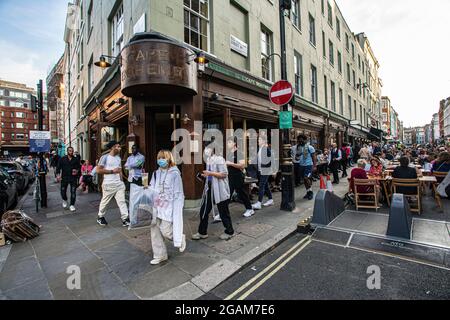 People celebrating 'freedom day' ending over a year of COVID-19 lockdown restrictions in England people drinking on tables placed outside on  Old Comp Stock Photo