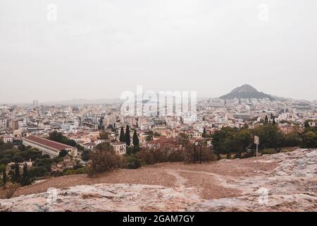 View on mount Lycabettus, Stoa of Attalos and Athens old city center with rocky hill in gray foggy day from Areopagus - Hill near Acropolis. Sepia sty Stock Photo