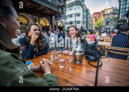 Young females celebrating 'freedom day' ending over a year of COVID-19 lockdown restrictions in England people drinking on tables placed outside on Ol Stock Photo