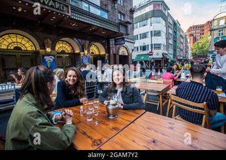 Young females celebrating 'freedom day' ending over a year of COVID-19 lockdown restrictions in England people drinking on tables placed outside on Ol Stock Photo