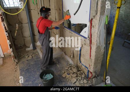 Mason removing a mirror from a wall. House renovation. Stock Photo
