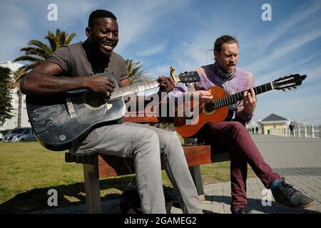 Fellow musician and friend Nog (right) joining Tom Sibanda (left) on a quest to raise funds to pay his rent on the last day of the month. Stock Photo