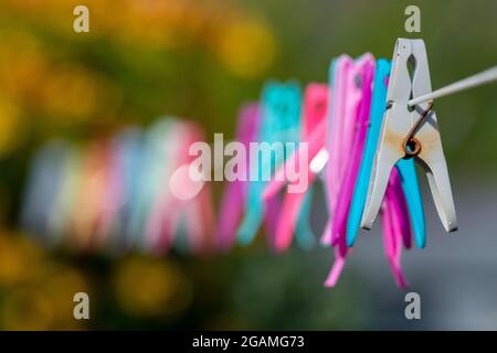 clothes pegs, plastic clothes pegs on a washing line, washing line with coloured pegs, colourful plastic clothes pegs, defocussed technique. Stock Photo