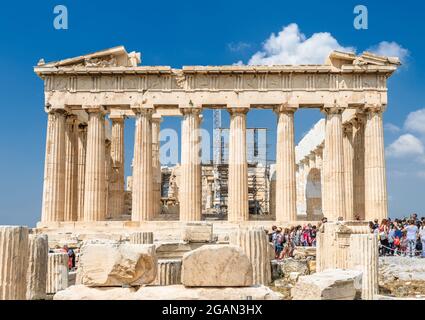 People visit Parthenon on Acropolis on sunny day, Athens, Greece. It is top tourist attraction of Athens. Ancient Greek ruins on