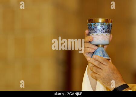 Communion rite during mass in a Catholic church. Priest chalice with wine to the faithful Stock Photo