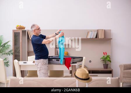Old male tourist preparing for trip at home Stock Photo