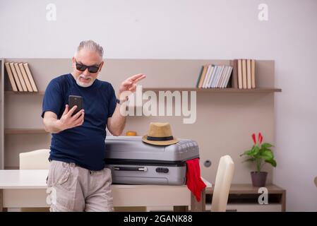 Old male tourist preparing for trip at home Stock Photo