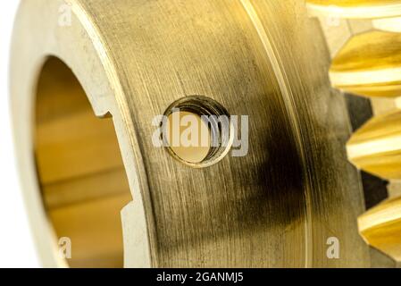 A macro photo of a new shiny copper gear, isolated on a white background, visible hole for the locking screw. Stock Photo