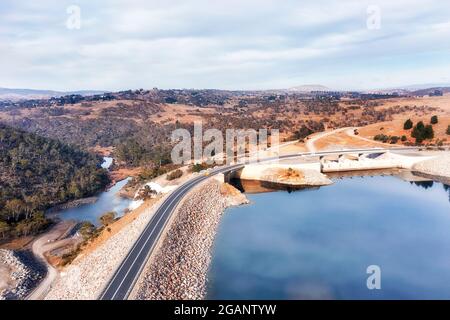 Bridge over concrete dam for highway across Snowy River forming Jindabyne lake in Snowy Mountains of Australia - aerial view. Stock Photo