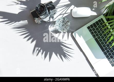 Laptop and vintage film camera with sun shadow. Home office workplace flat lay Stock Photo