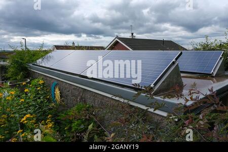 Solar panels on a shed roof in a garden on a cloudy day. Stock Photo