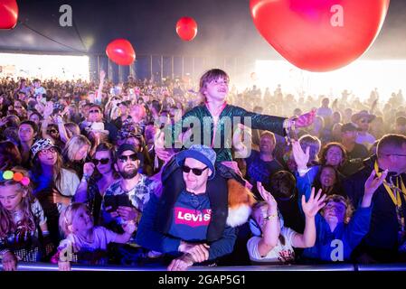 Lulworth, Dorset UK, Saturday, 31st July 2021 A girl on her Father's shoulders in the Big Top during Jo Wiley's DJ set, on Day 2 of Camp Bestival, Lulworth Castle, Dorset. Credit: DavidJensen / Empics Entertainment / Alamy Live News