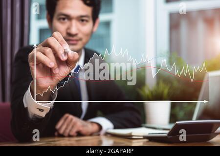 Business man sitting on desk writing growth chart graph finance at him office Stock Photo